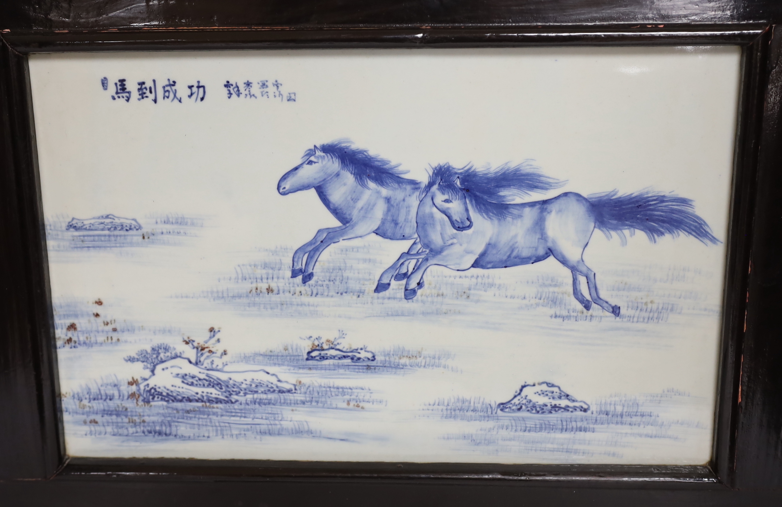A Chinese framed blue and white porcelain panel depicting two horses, framed, overall 35 x 48cm